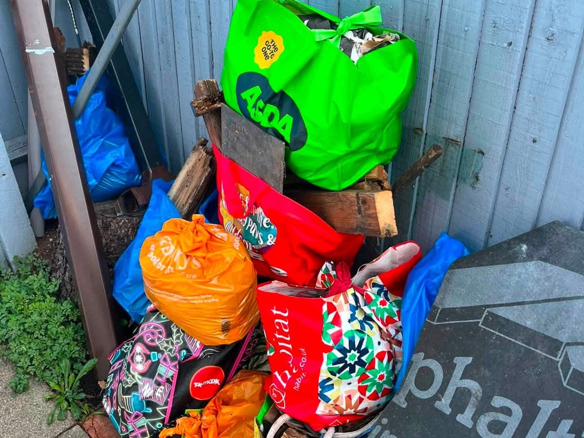 Bags of household rubbish, bedding and timber piled up in a side passage before removal