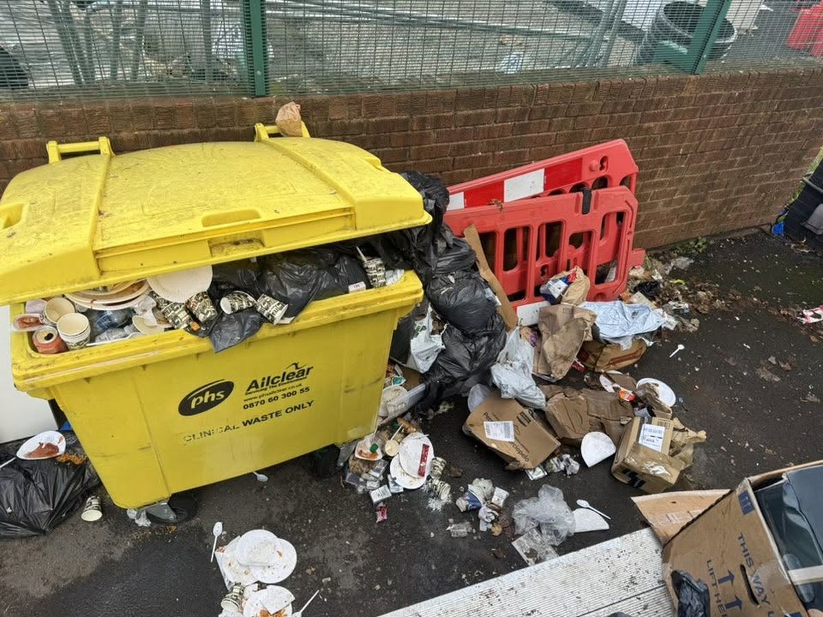 Overflowing commercial bin surrounded by spilled boxes, bags and waste before clearance