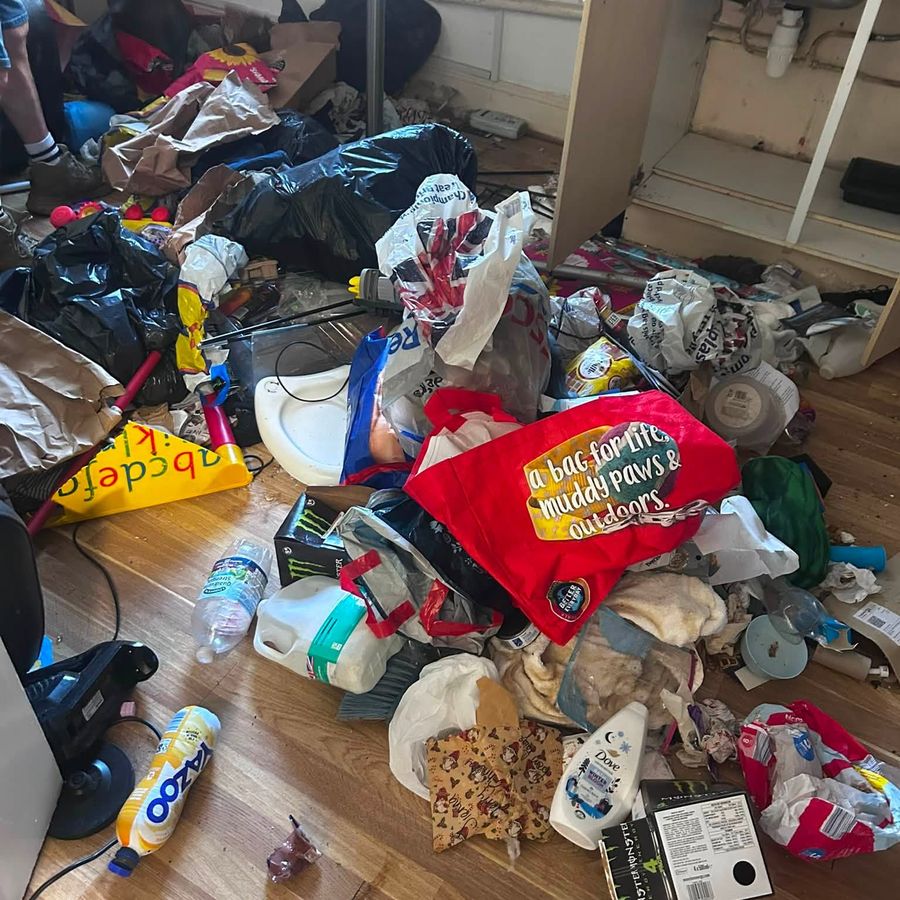 Flat floor covered in bags and household waste being cleared by hand